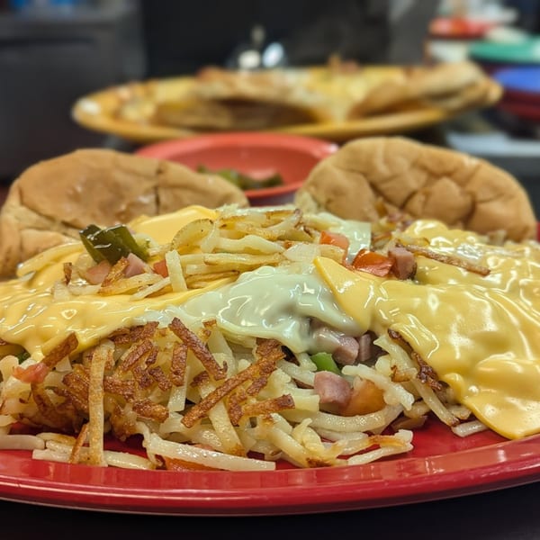 Waffle Shoppe's breakfast skillet with hash browns, melted cheese, ham, peppers, and two buns.
